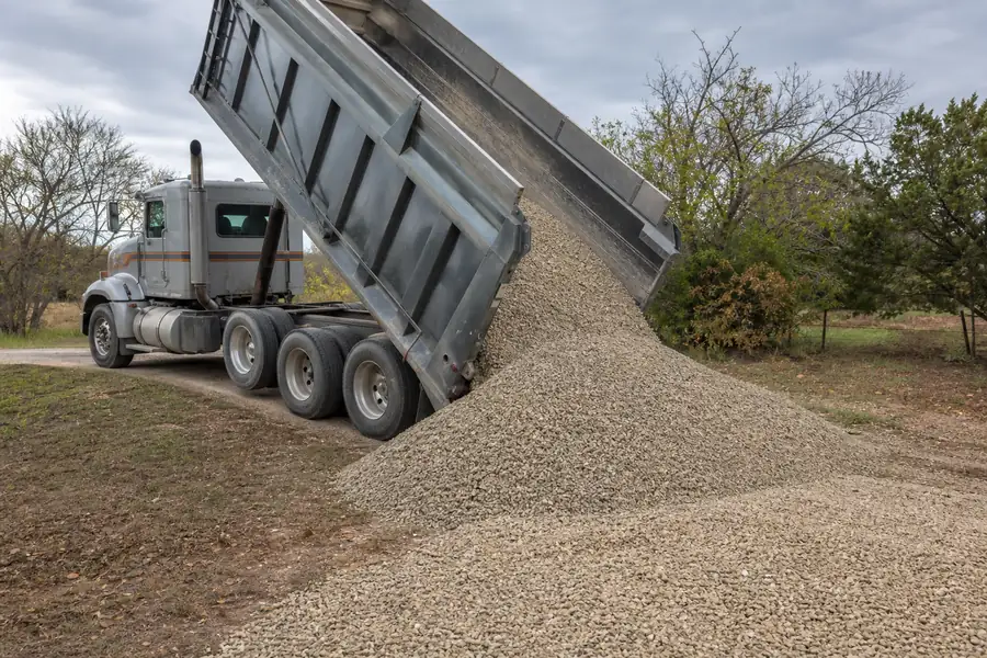 Dump truck delivering flex base gravel to a rural Texas driveway