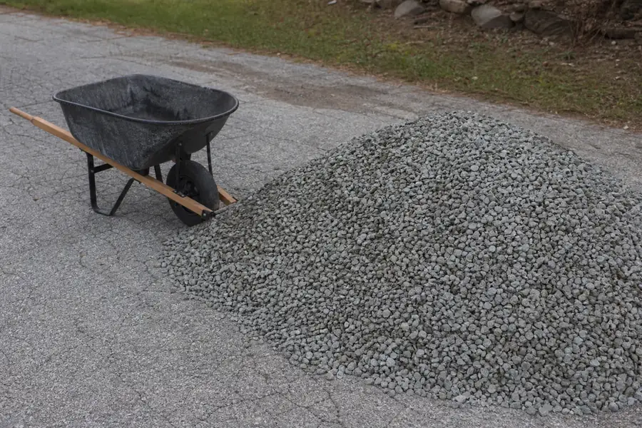One cubic yard of gravel dumped on a driveway next to a wheelbarrow
