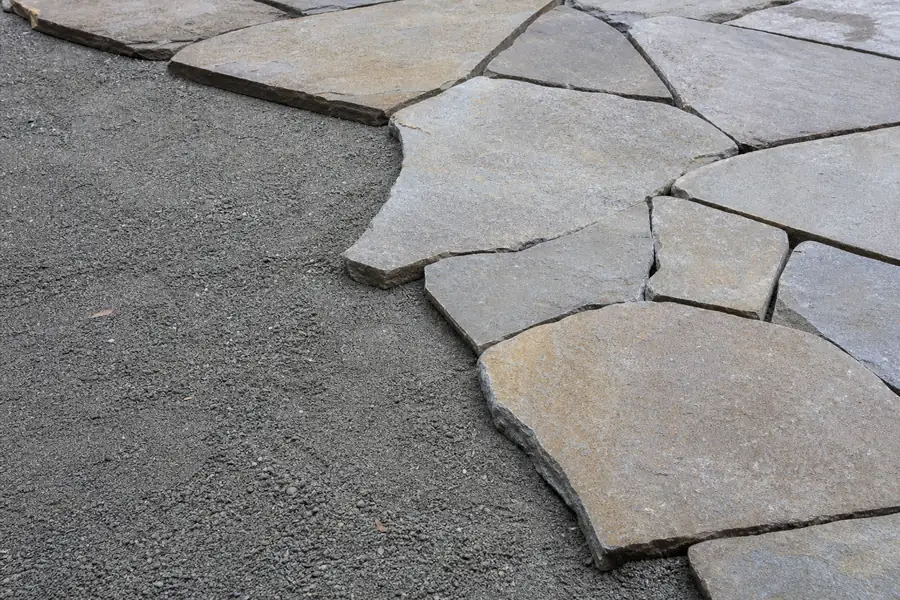 Flagstone being set on a bed of compacted screenings