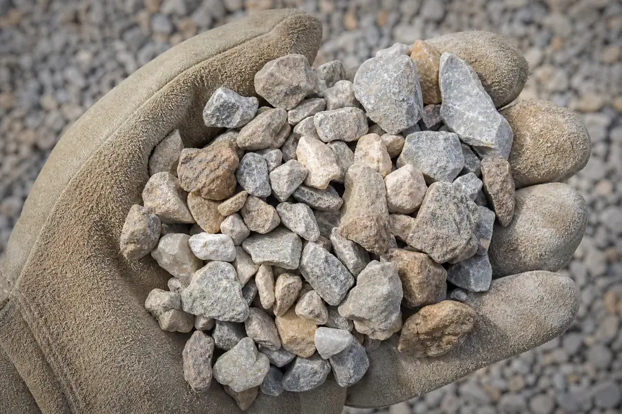 Mixed crushed limestone gravel in a gloved hand, Texas sun